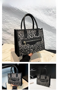 Detail of black and white leopard print tote bag with dual leather handles and metallic zipper