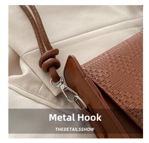 Detail of silver metal lobster clasp and textured brown woven leather on a shoulder bag