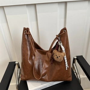 Sac à bandoulière hobo vintage marron avec breloque ours sur fond blanc minimaliste