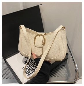 Detail of beige pebble leather shoulder bag featuring a large gold metal buckle