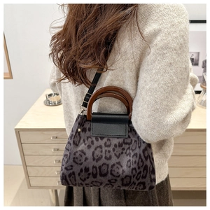 Dettaglio borsa a tracolla leopardata con manico ad anello in legno indossata da modella