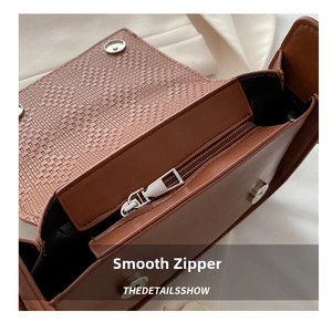 Detail of caramel brown handbag featuring woven texture flap and smooth metal zipper