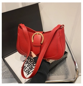 Close-up of red lychee pattern leather bag with large golden horseshoe metal buckle