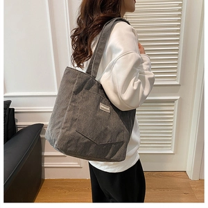 Detail showing the dark gray corduroy texture and front pocket of the tote bag