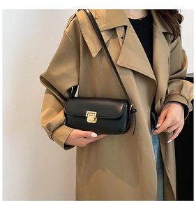 Gros plan d'un petit sac carré noir mat avec fermoir doré porté par un mannequin