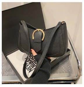 Close-up of black lychee grain leather shoulder bag with golden horseshoe buckle detail
