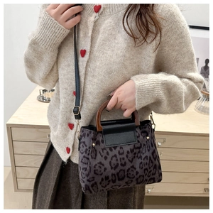 Detail view of leopard print crossbody bag with wooden handle and gold metal studs