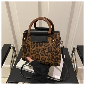 Detail of leopard print tote bag featuring brown resin ring handle and black leather flap