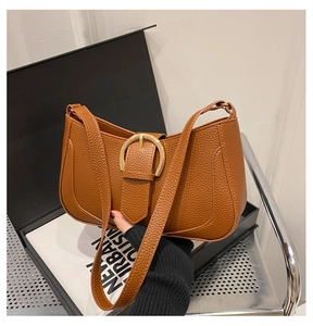 Detail of caramel crescent shoulder bag featuring pebbled texture and gold metal buckle