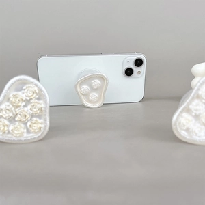 Detail of elegant white 3D pearl rose flower relief on a foldable phone socket grip
