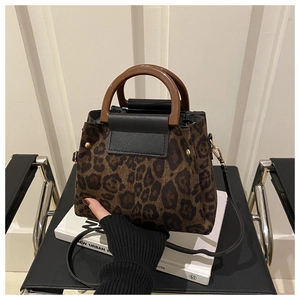 Detail of leopard print handbag with black leather flap and metal stud accents