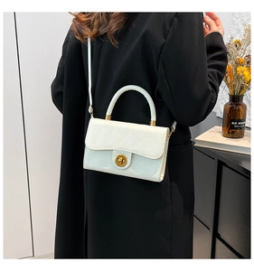 Detail of white leather handbag with gold twist lock and shoulder strap on a model