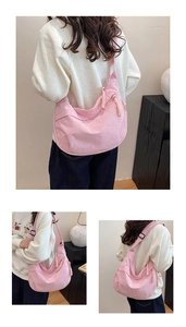 Detail view of pink corduroy crescent bag showing soft ribbed texture and strap