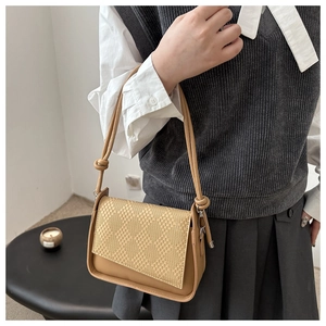Detail of khaki shoulder bag with woven texture flap and decorative knotted rope strap