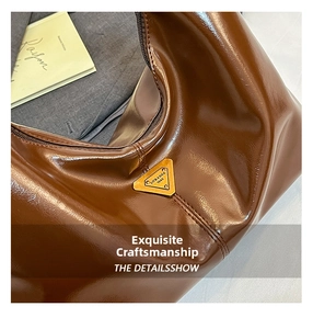 Macro shot of brown glossy leather bag featuring a vintage triangular metal logo plaque