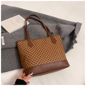 Detail of vintage tote bag with geometric pattern on a gray coat backdrop