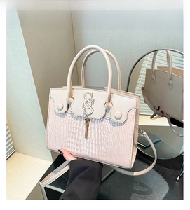 Close-up of khaki crocodile pattern leather bag with gold S-pendant and chain tassel