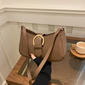 Brown lychee leather underarm bag with gold horseshoe buckle in cozy cafe setting