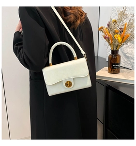 Chic white leather handbag with golden twist lock shown in a lifestyle interior setting