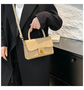 Détail d'un sac à bandoulière crème chic avec fermoir doré et poignée supérieure élégante