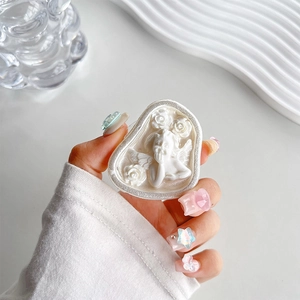 Detail of cream white resin heart phone grip featuring embossed angel and rose motifs