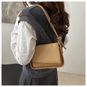Detail of khaki shoulder bag with woven flap design and decorative side knots