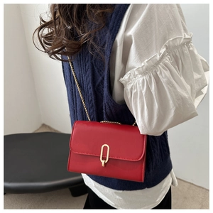 Borsa a tracolla rossa in ecopelle con catena dorata e chiusura a scatto sulla modella
