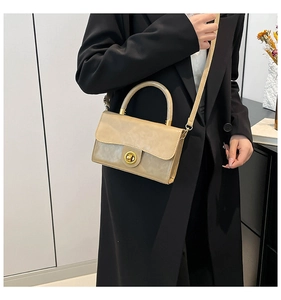 Close-up of beige vintage handbag with golden twist lock on a black blazer model