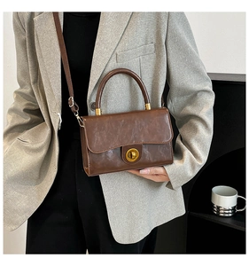Détail du sac rétro marron foncé avec texture polie et fermoir rotatif doré élégant