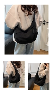 Detail of black corduroy dumpling bag featuring wide shoulder strap and woven zipper puller