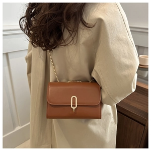 Borsa a tracolla quadrata marrone con catena dorata abbinata a un trench