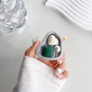 Macro shot of silver grip tok with pearl, cream heart and green resin gems on a phone