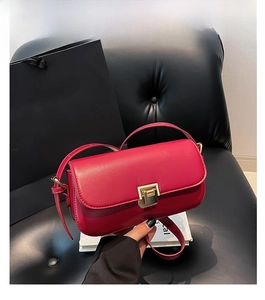 Detail einer magentaroten Ledertasche mit goldener Schnalle auf einer schwarzen Bank