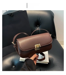 Detail einer kaffeebraunen Lederklapptasche mit quadratischer goldener Metallschnalle
