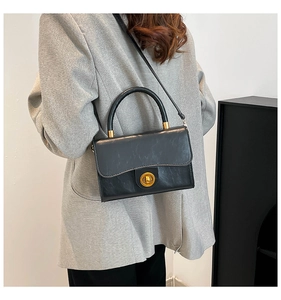 Side view of woman carrying a black vintage pleated handbag with gold twist lock