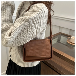 Detail of retro brown shoulder bag with woven texture and decorative knotted strap