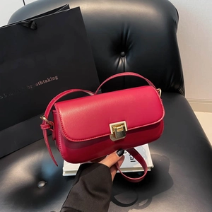 Petit sac à bandoulière rouge rose avec boucle dorée présenté dans un décor luxueux