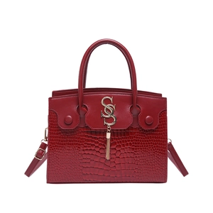 Sac à main rouge élégant en cuir gaufré crocodile avec logo S doré et pompon chic