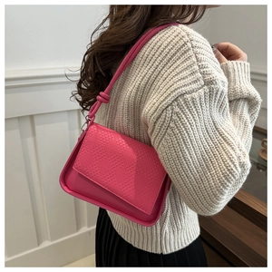 Detail of fuchsia crossbody bag with woven texture flap on a knit sweater outfit