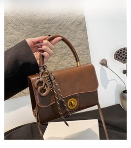 Retro brown leather square handbag featuring gold twist lock and woven rope pendant