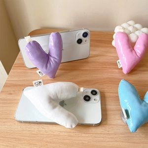 Padded heart-shaped leather phone grip in pastel colors on wooden surface