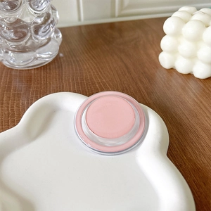Detail of soft pink cream blush in a round clear case on a cloud-shaped tray