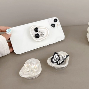 Foldable butterfly and cherry cell phone grip stand on a white heart base for desk