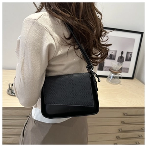 Detail of black woven texture shoulder bag with minimalist strap and silver buckle
