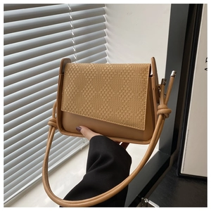 Detail of woven texture on khaki leather handbag flap with knotted strap accent
