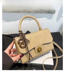 Detailansicht khakifarbene PU-Handtasche mit goldenem Drehverschluss und rundem Griff