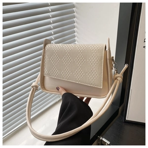 Close-up of cream woven texture and smooth leather finish on a stylish handbag