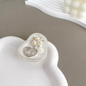 Detail of heart-shaped phone grip with gray resin heart, white rose and pearls