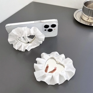 Close-up of heart-shaped vanity mirror phone grip with white satin ruffled lace edges