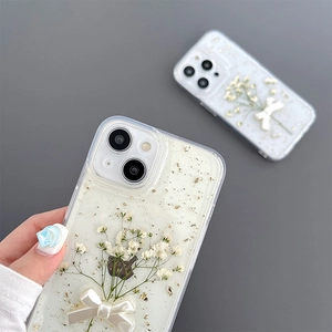 Detail of iPhone case with real dried flowers, gold foil, and a 3D pearly bow decoration